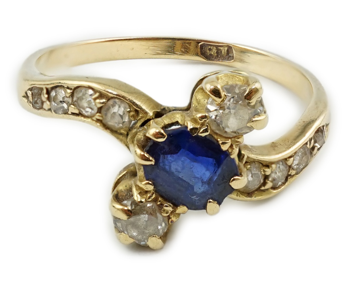 An 18ct gold, sapphire and diamond set three stone crossover ring, with eight stone graduated diamond set shoulders